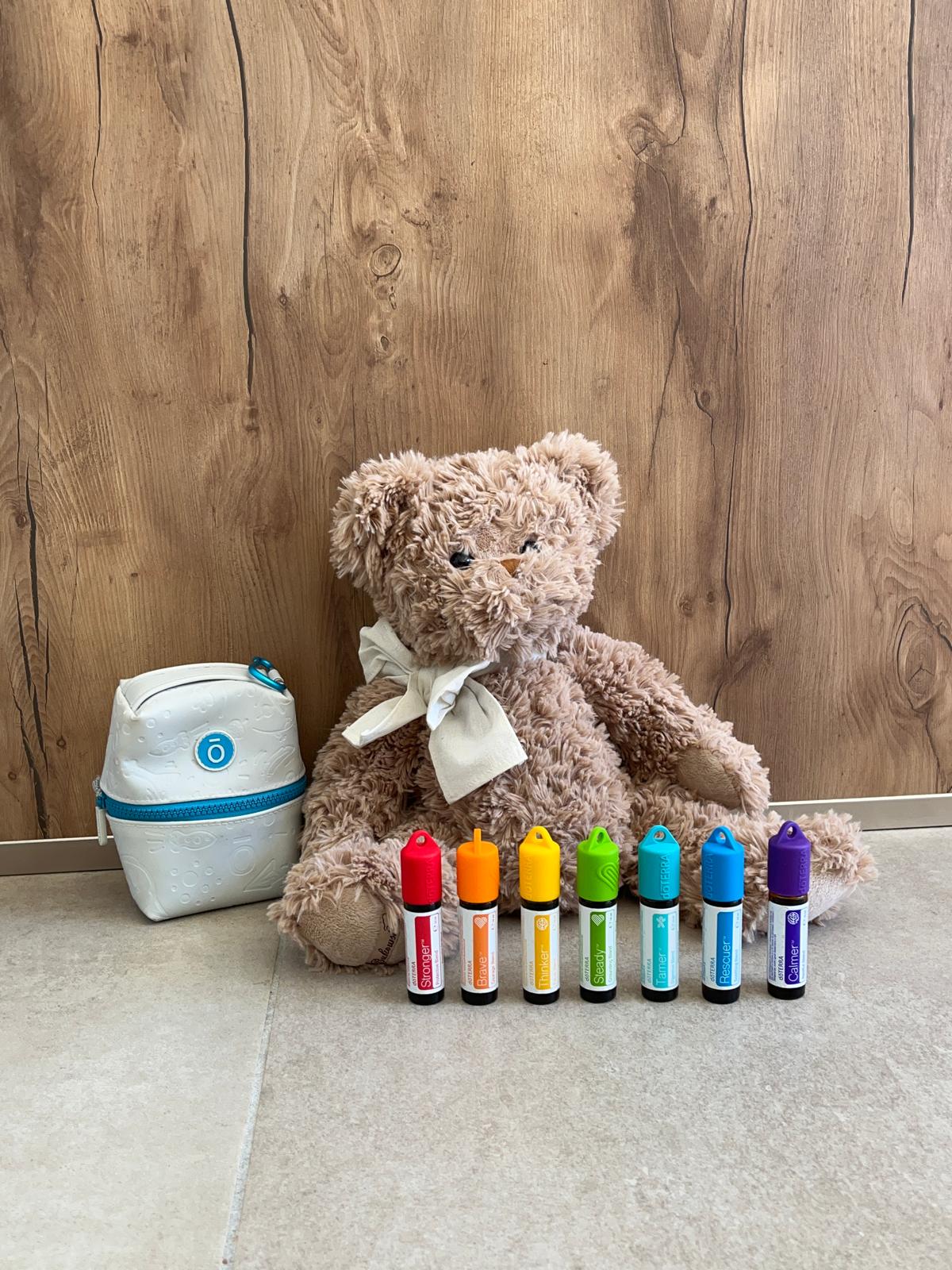 Les sept roll-on colorés du Kit Enfant alignés devant un ourson en peluche